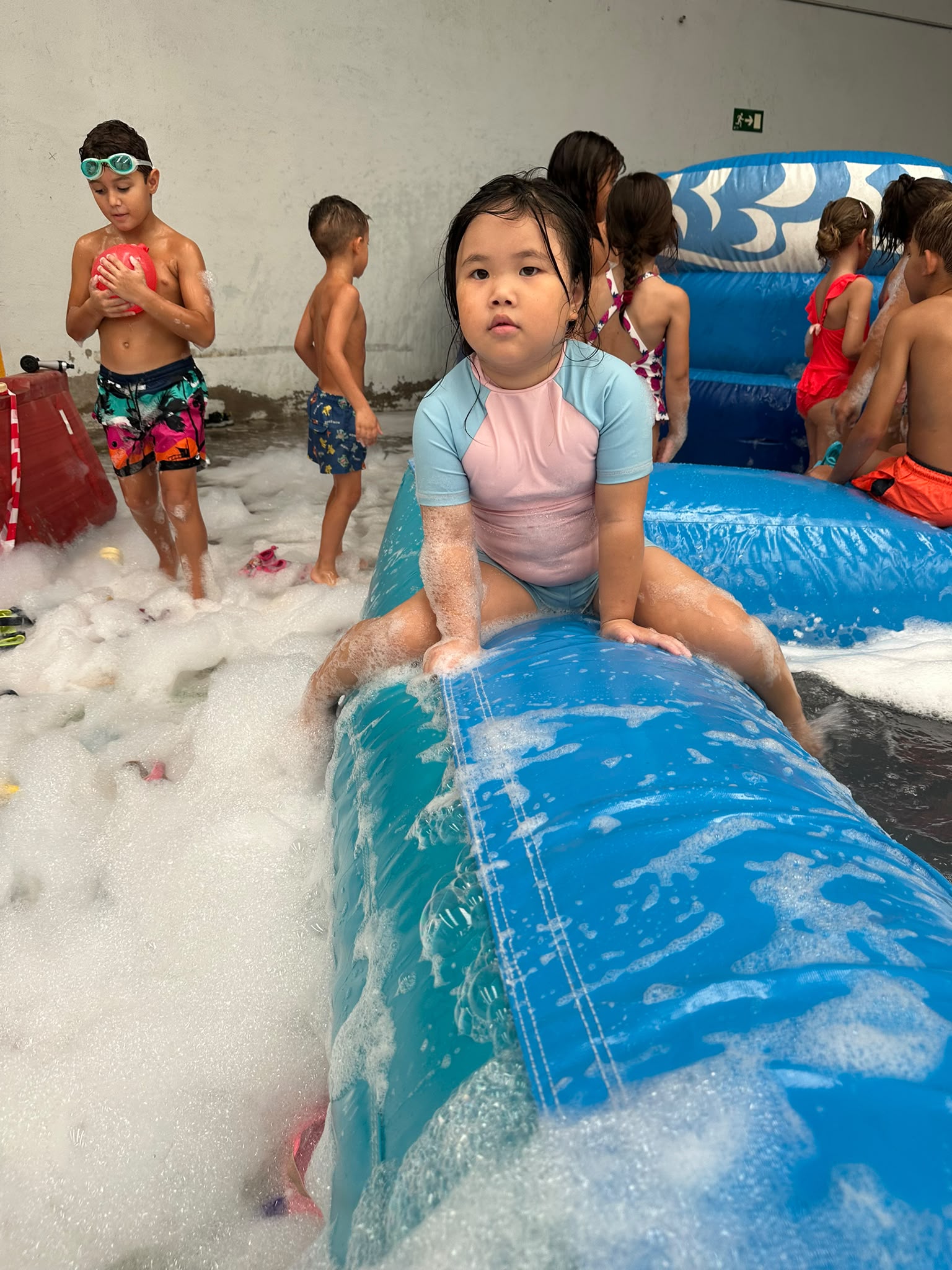 Niños jugando en una deslizadora con agua y espuma